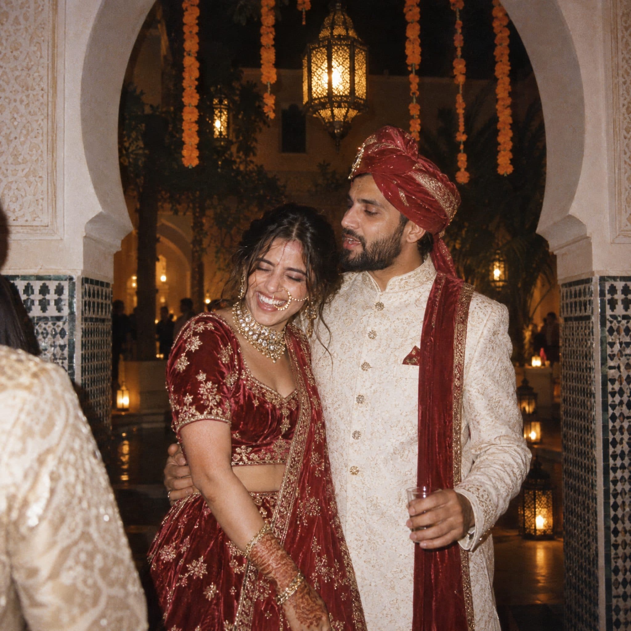 Couple under a Moorish arch hung with marigold garlands after the ceremony