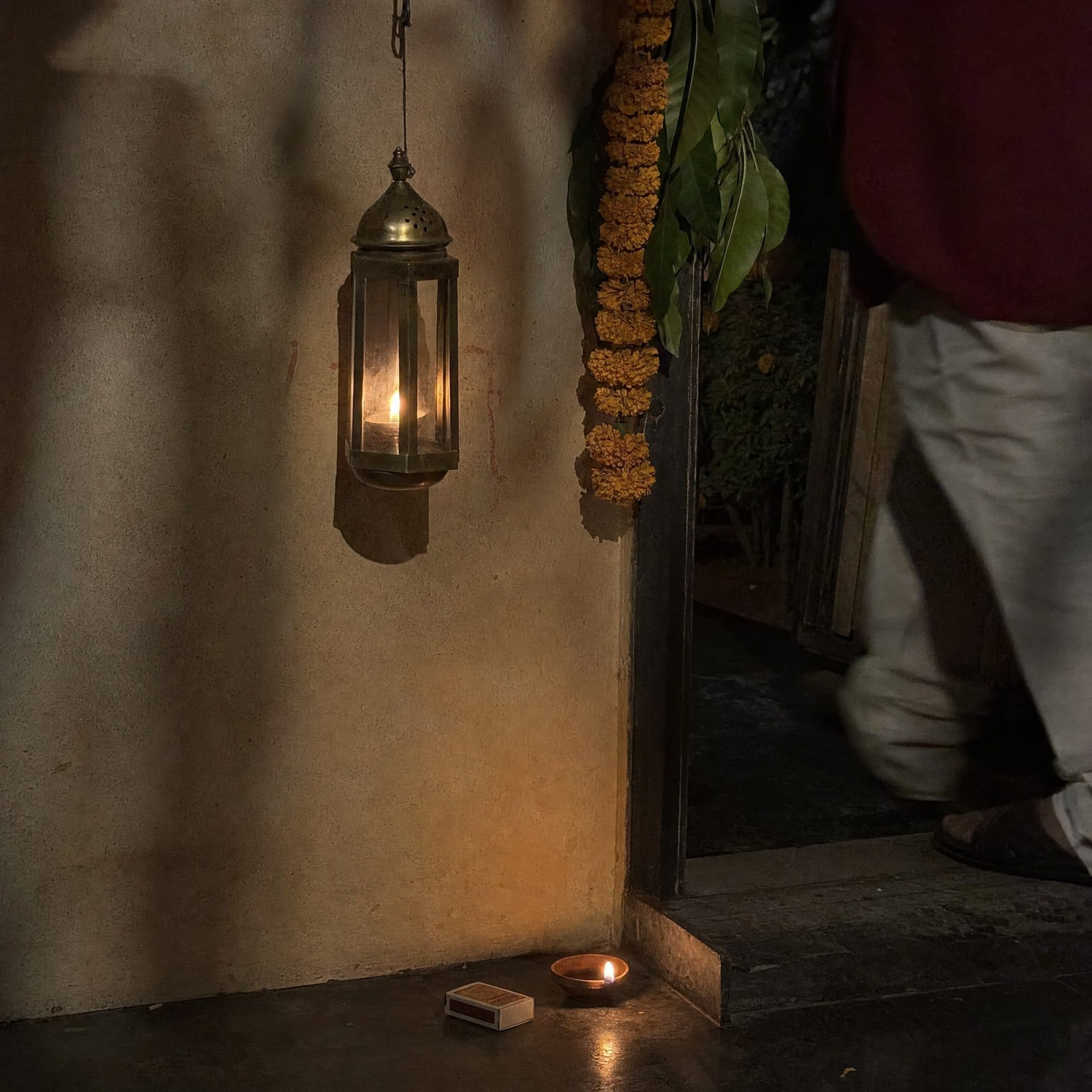 Brass lantern and marigold garland hanging against an ochre wall