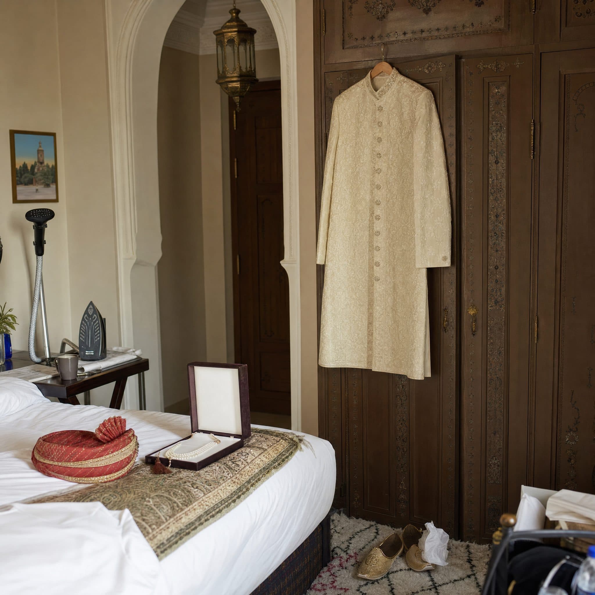 Groom's cream sherwani hanging ready in a palace suite beside his turban