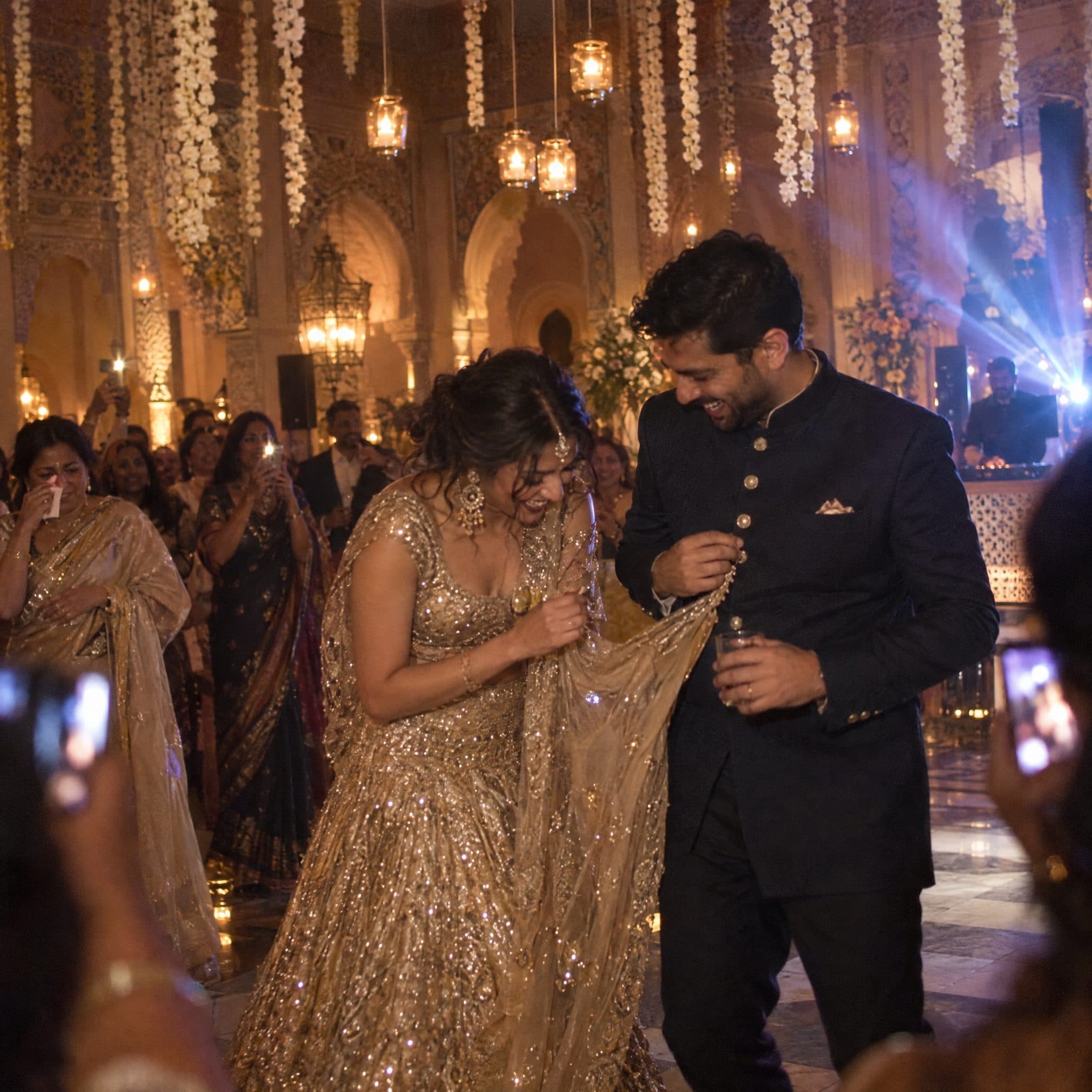 Couple dancing among guests under hanging florals at the reception