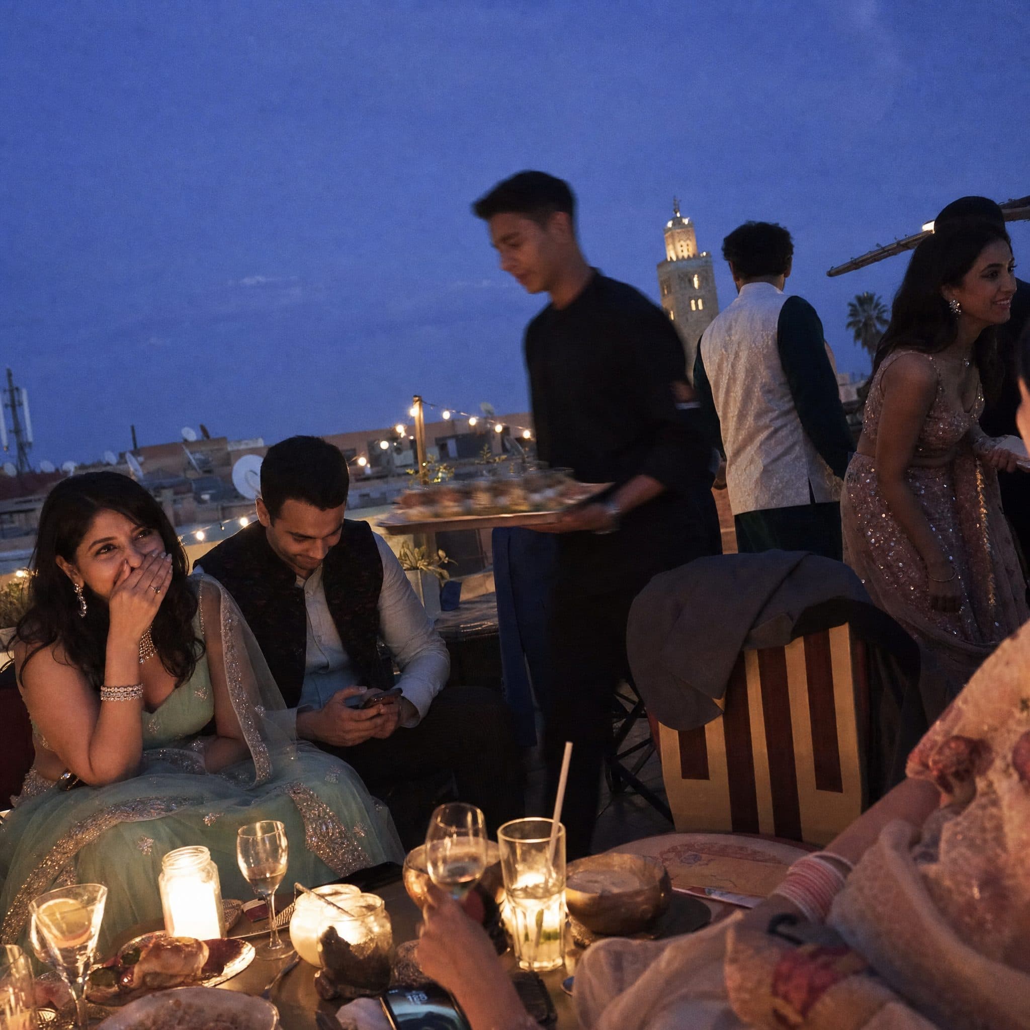 Guests at rooftop welcome drinks at dusk with the Koutoubia minaret behind